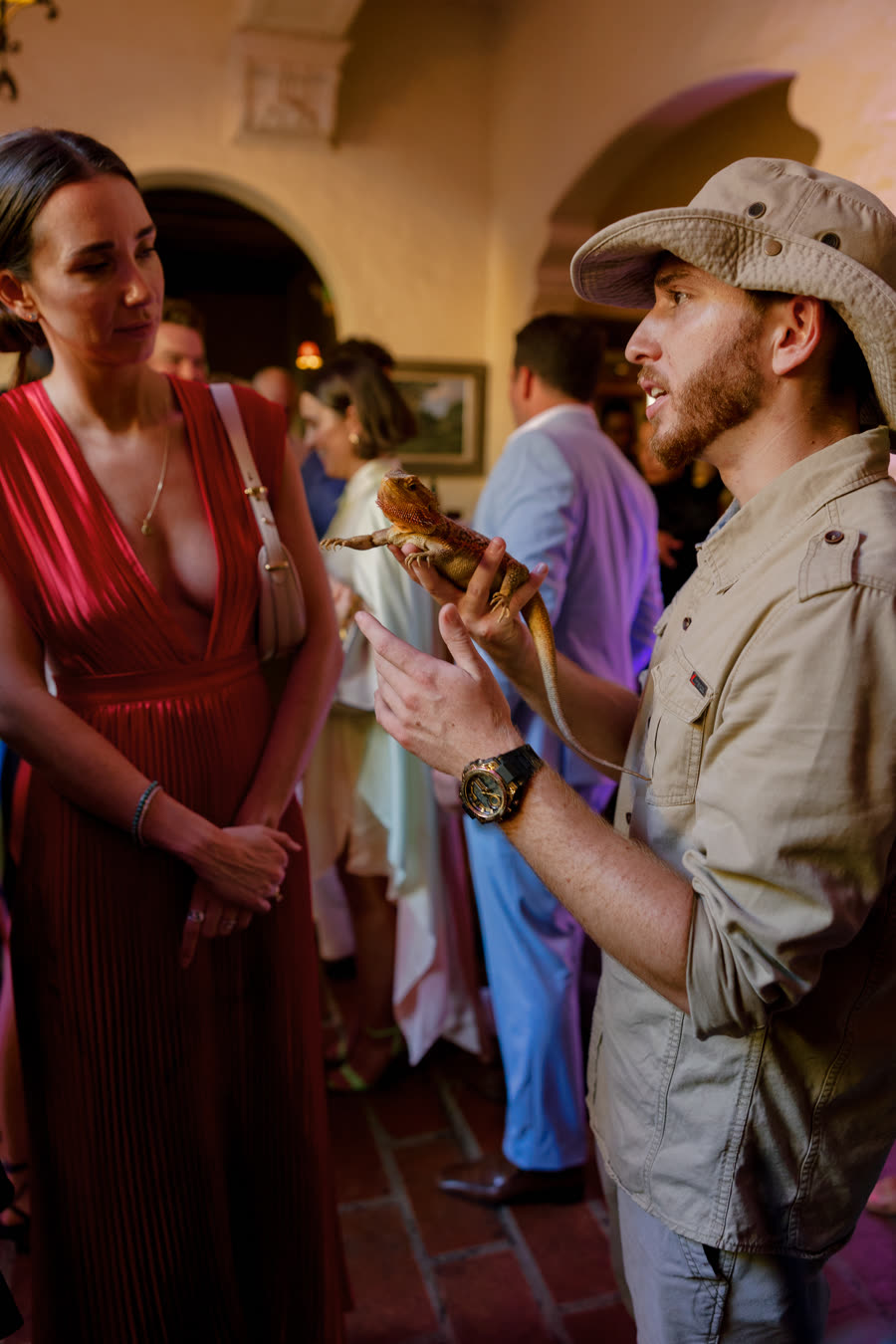 Handler introducing a bearded dragon to guests at an elegant Miami evening event